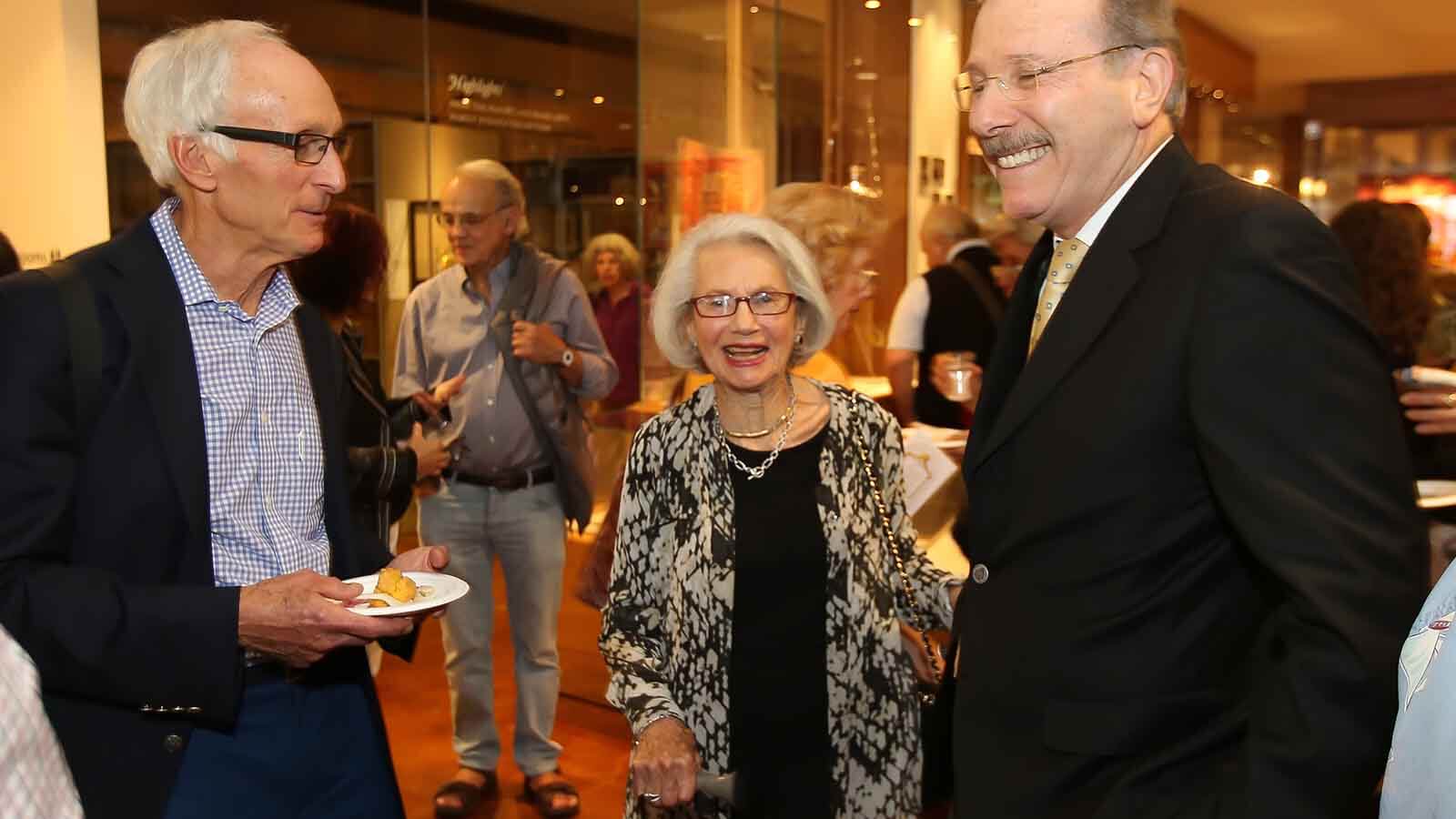 a woman and 2 men in a exhibition reception