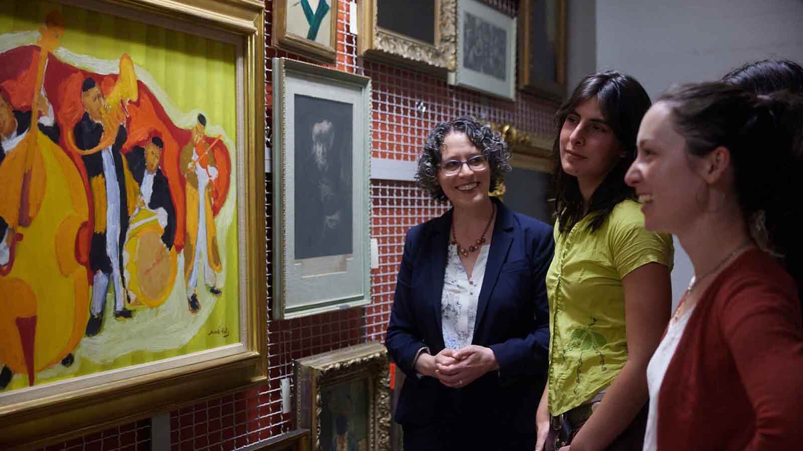 3 people discussing a painting in Magnes storage